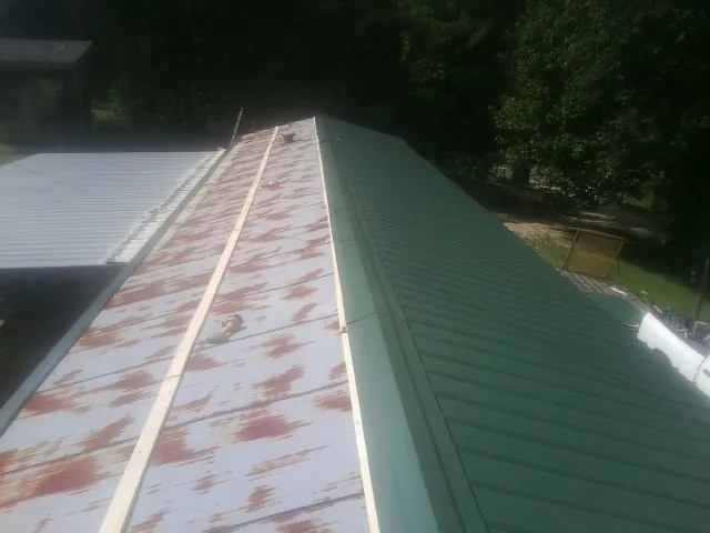 Old rusted panels beside newly installed green metal roofing — Wind Damage Roof Repair by Roofing Brothers in Palm Desert