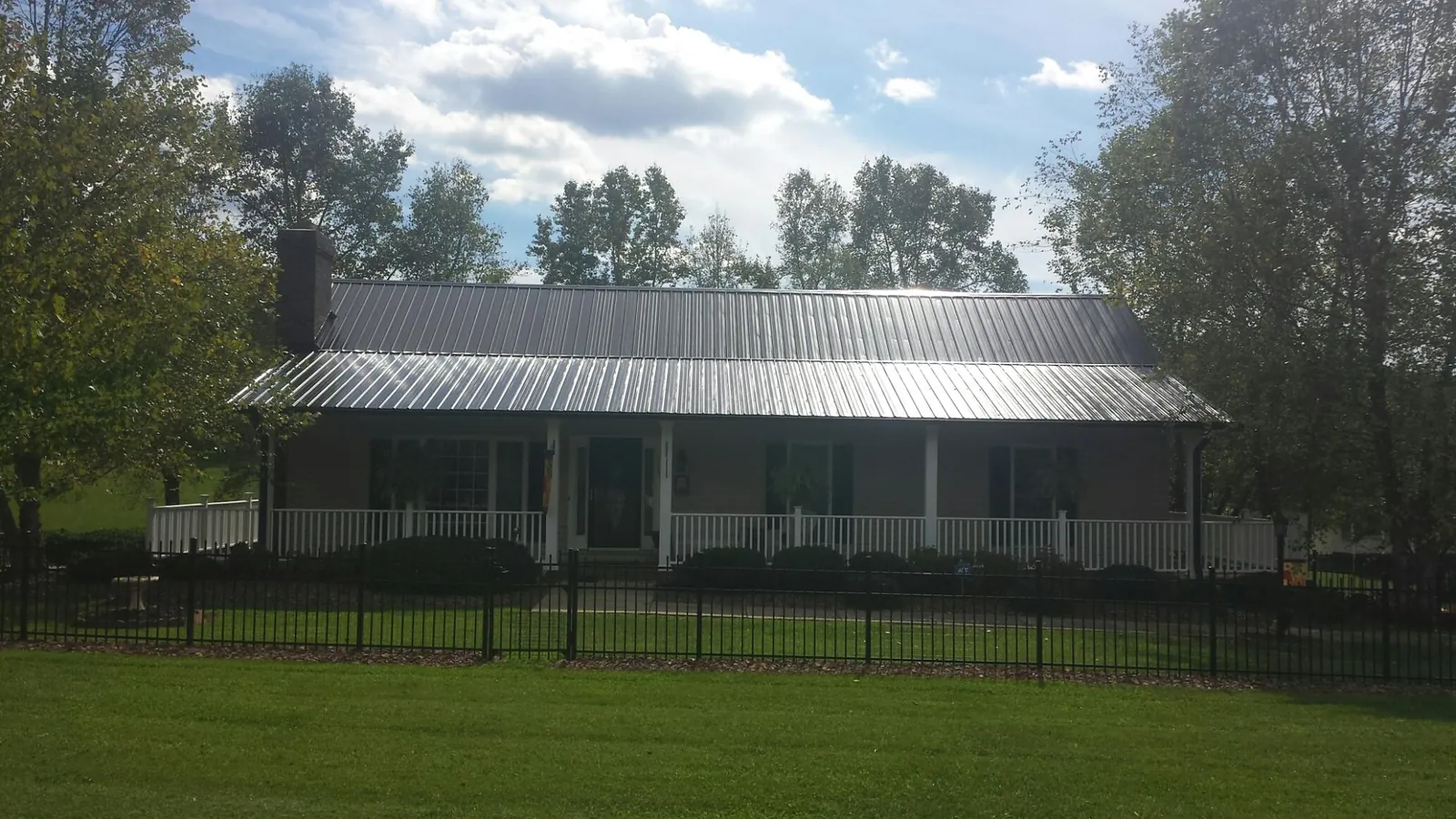 Gray metal roof on a brick ranch with a full width front porch — Gutter Guard Installation work by our crew in Palm Desert