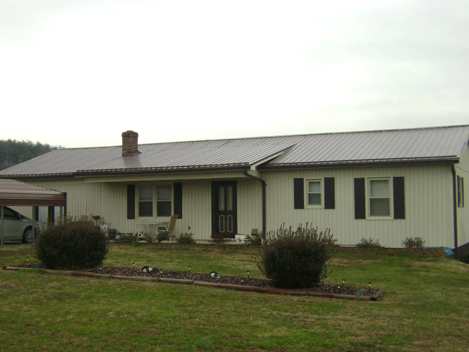 Brown metal roof on a cream sided ranch home with a brick chimney in Palm Desert